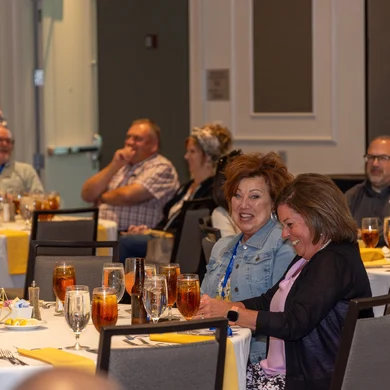 Audience members laughing and smiling at a corporate banquet during Josh Fletcher's mentalism show