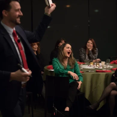 Josh Fletcher performing mentalism at a corporate dinner event as a woman in green reacts with amazement