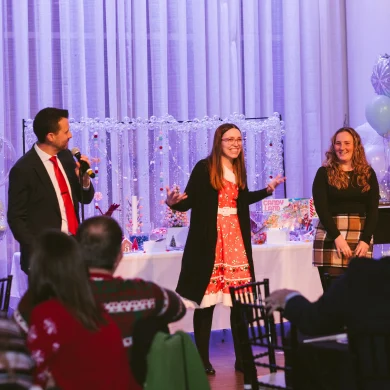 Josh Fletcher performing mentalism on stage with two audience volunteers at a holiday corporate event