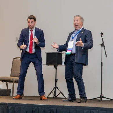 Josh Fletcher performing mentalism on stage with an excited ICCMO volunteer
